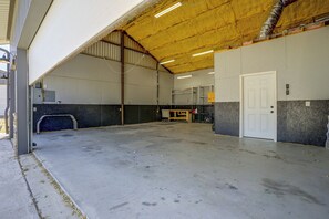 An industrial interior with a concrete floor, metal beams, and a door on the right. - Countryside Home Right Outside Fort Worth (Joshua)