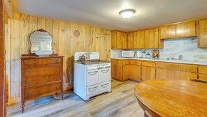 A kitchen with wooden cabinets, a stove, a microwave, and a wooden dining table. - Yuba River Retreat for 2! Near Swimming Holes (Washington)