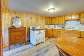 A kitchen with wooden cabinets, a stove, a microwave, and a wooden dining table. - Yuba River Retreat for 2! Near Swimming Holes (Washington)