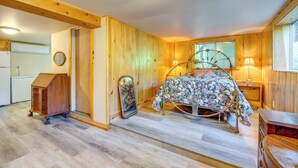 A bedroom with a wooden floor, a bed with a floral bedspread, a dresser, and a window with a view. - Yuba River Retreat for 2! Near Swimming Holes (Washington)