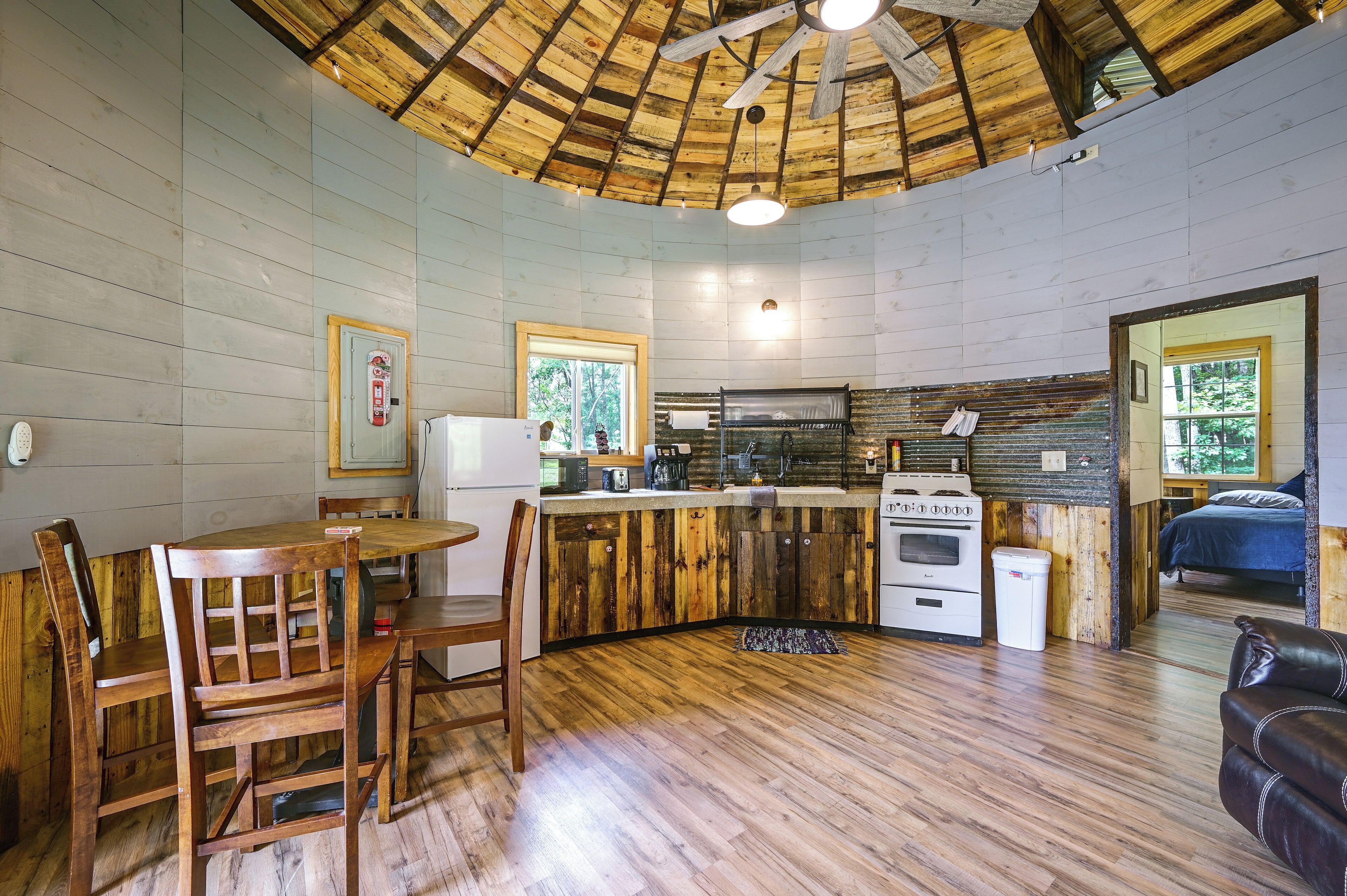 A compact kitchen with wooden cabinets, a dining area with a table and chairs, and a ceiling fan.