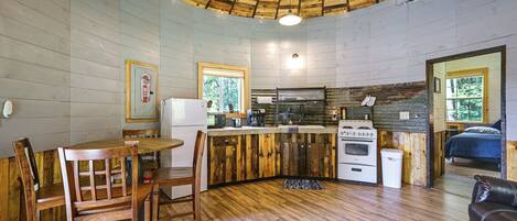 A compact kitchen with wooden cabinets, a dining area with a table and chairs, and a ceiling fan.