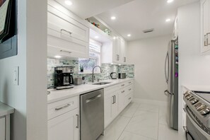 A modern kitchen with stainless steel appliances, white cabinetry, and a tiled backsplash. - Delray Beach Oasis! Screened Lanai & Private Pool (Delray Beach)