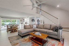 A modern living room with a sectional sofa, a coffee table, and a dining area with chairs. - Delray Beach Oasis! Screened Lanai & Private Pool (Delray Beach)