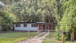 A single-story house with a front porch, a mailbox, and a chain-link fence.