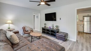 A living room with a sofa, a coffee table, a chair, a television, and a ceiling fan.