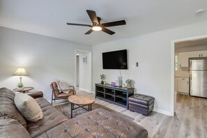 A living room with a sofa, a coffee table, a chair, a television, and a ceiling fan. - Walk to FSU Campus & Stadium! Tallahassee Home (Tallahassee)