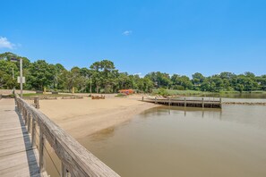 A wooden pier extending into a calm lake with a sandy beach and trees in the background. - Condo Close to Busch Gardens/Colonial Williamsburg (Williamsburg)