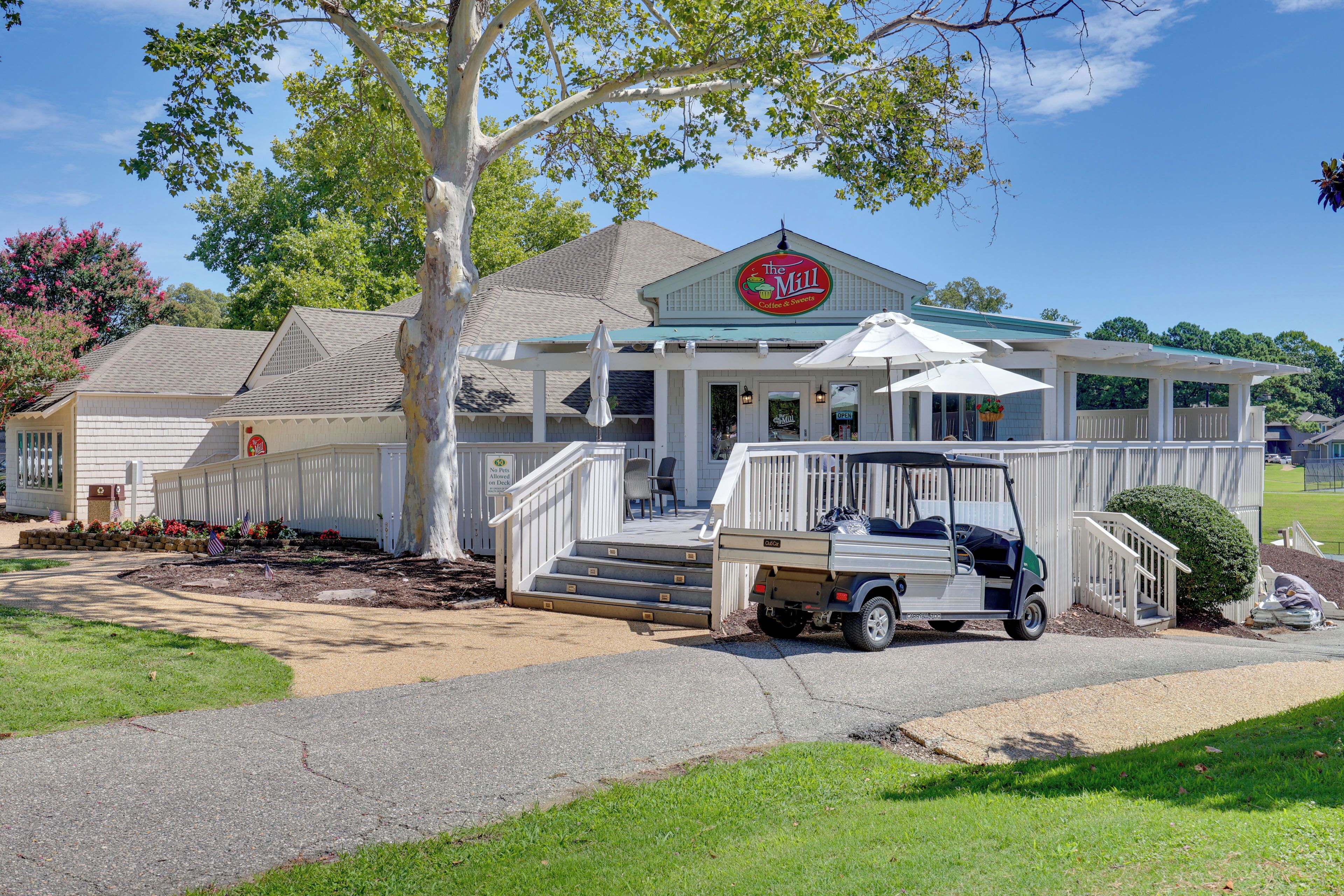A two-story building with a porch, a sign reading 'The Mill Coffee & Sweets', and a golf cart parked in front.