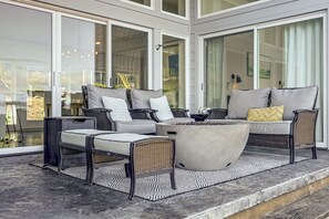 A modern outdoor seating area with wicker furniture and a fire pit. - Peaceful Waterfront Retreat on Vashon Island (Vashon)