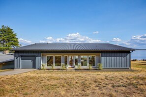 A modern single-story house with a garage, large windows, and a view of a lake. - Peaceful Waterfront Retreat on Vashon Island (Vashon)