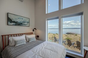 A bedroom with a bed, a painting, and a view of the beach. - Peaceful Waterfront Retreat on Vashon Island (Vashon)
