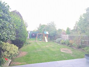 A backyard with a swing set, a slide, and a playhouse.