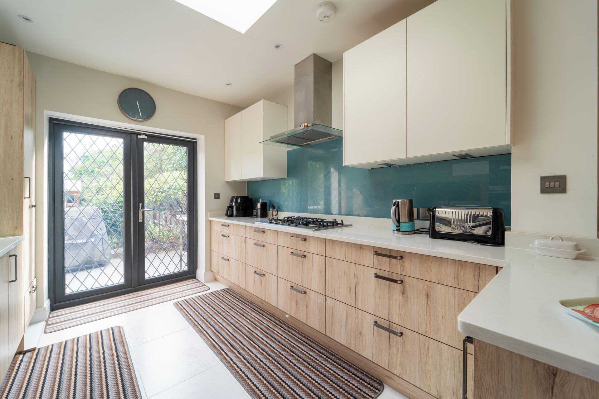 A modern kitchen with a gas stove, a toaster, and a clock on the wall.
