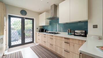 A modern kitchen with a gas stove, a toaster, and a clock on the wall.