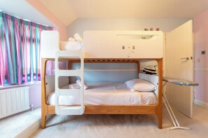 A bunk bed with a ladder, a small shelf, and a door with a radiator.