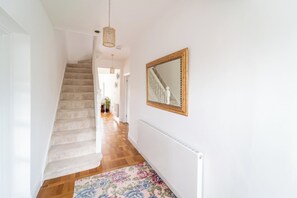 A staircase leading to a landing with a mirror and a hanging light fixture. - Extended Family Home with Parking near Heathrow (Ickenham)