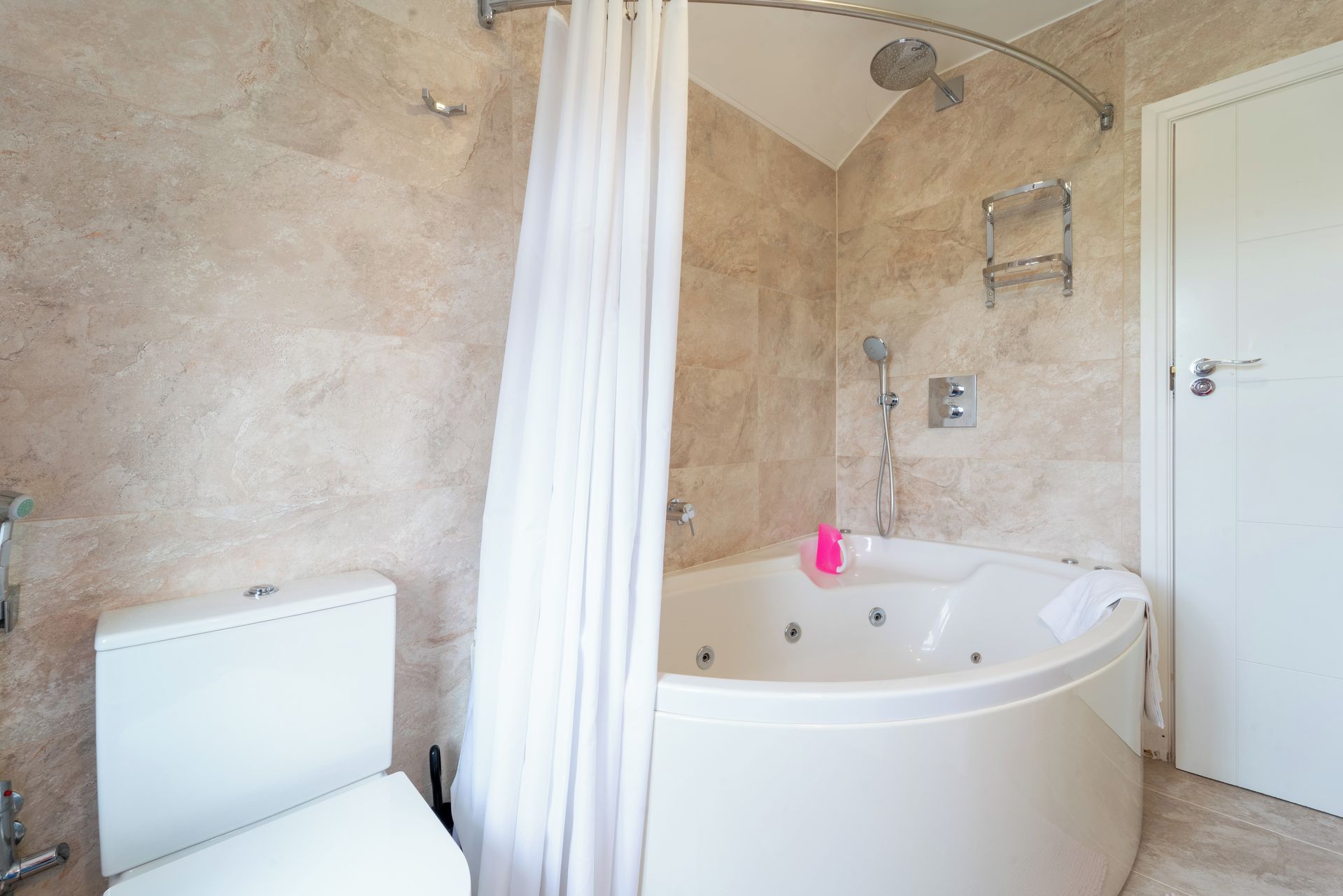 A bathroom with a bathtub, shower, toilet, and a door.