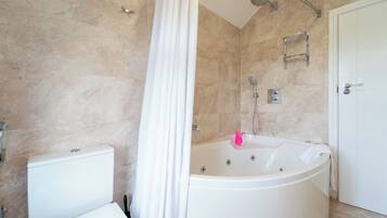 A bathroom with a bathtub, shower, toilet, and a door.