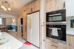 A modern kitchen with wooden cabinets, a white refrigerator, and a double oven.