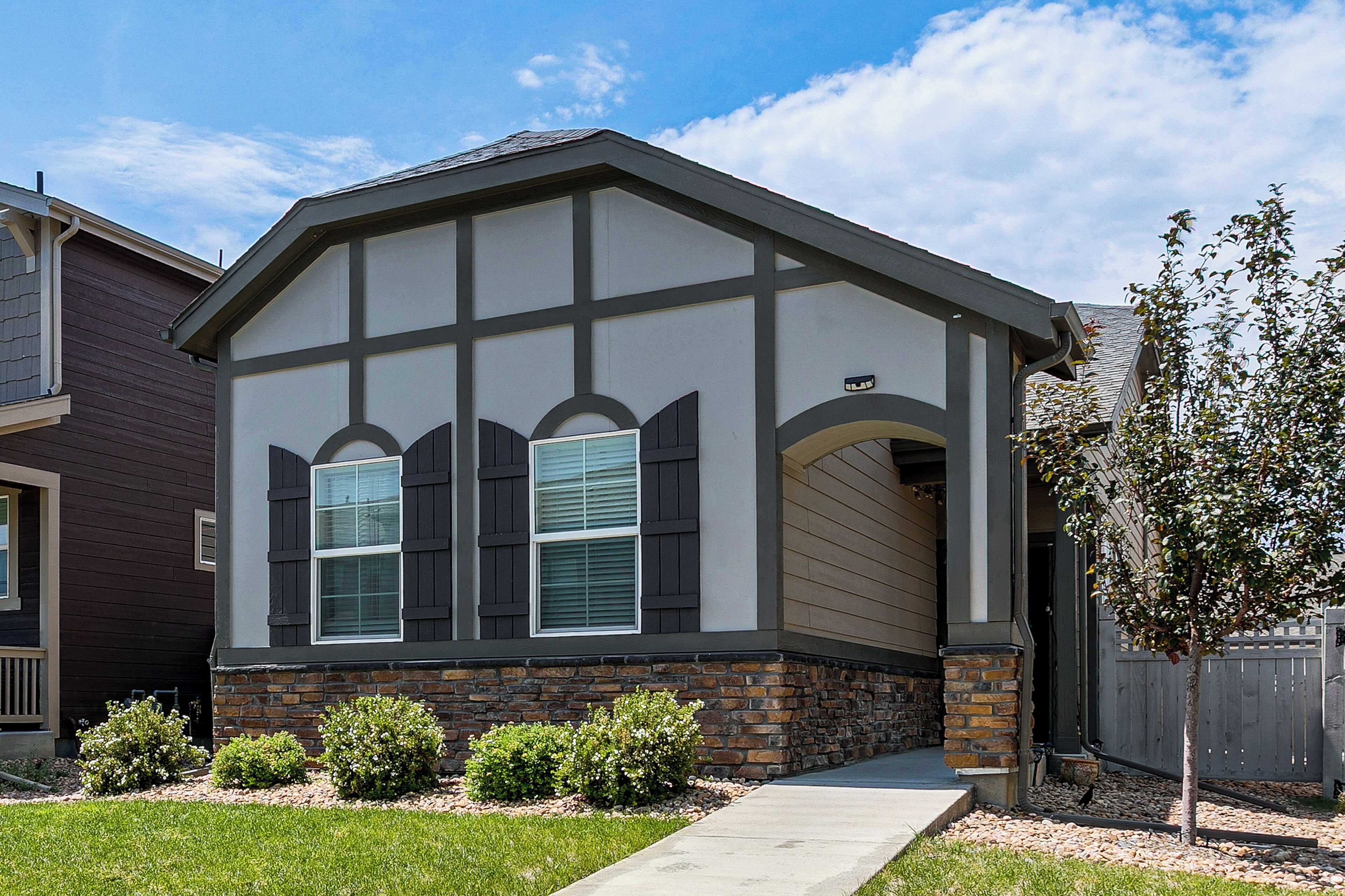 A residential house with a stone foundation, a gabled roof, and a front porch.