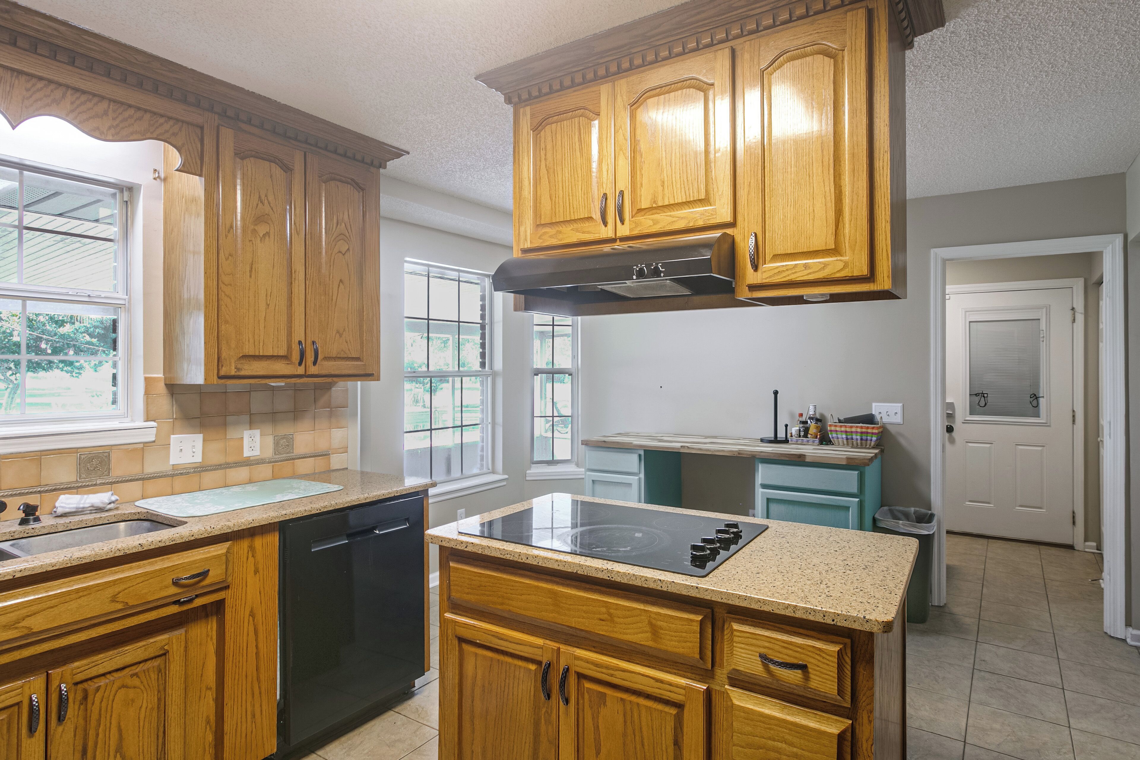 A kitchen with wooden cabinets, a dishwasher, a stove, and a window.