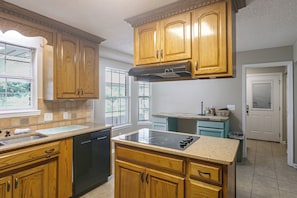 A kitchen with wooden cabinets, a dishwasher, a stove, and a window. - Fish, Swim & Soak: Rural Lakeland Retreat (Lakeland)