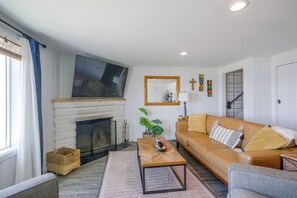 A living room with a fireplace, a sofa, a coffee table, and a television mounted on the wall. - Direct Beach Access, 2 Mi to Chinook Winds Casino (Lincoln City)