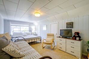 Ein Schlafzimmer mit einem Bett, einem Sessel, einem Fernseher und einem Teddybären.