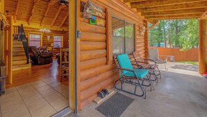 Uma cabana de troncos com varanda, um letreiro de boas-vindas e vista para a floresta ao redor.