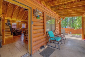Ein Blockhaus mit Veranda, einem Willkommensschild und Blick auf den umliegenden Wald.