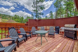 Une terrasse extérieure avec un barbecue, des chaises et une table.