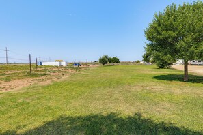 A grassy field with a tree and a building in the distance. - Hot Tub & Mtn Views! Carlsbad RV Retreat (Carlsbad)