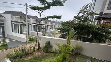 Un quartier résidentiel avec des maisons modernes, un jardin verdoyant agrémenté de pas japonais et un escalier menant à un niveau supérieur.