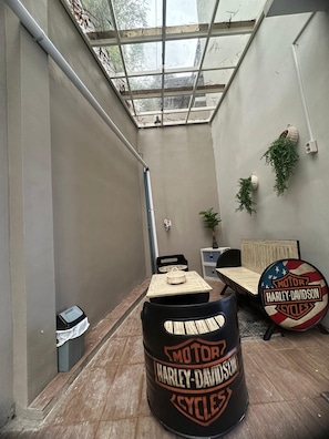 A narrow hallway with a skylight, a table with a basket, a Harley-Davidson barrel, and a bed with a Harley-Davidson logo.