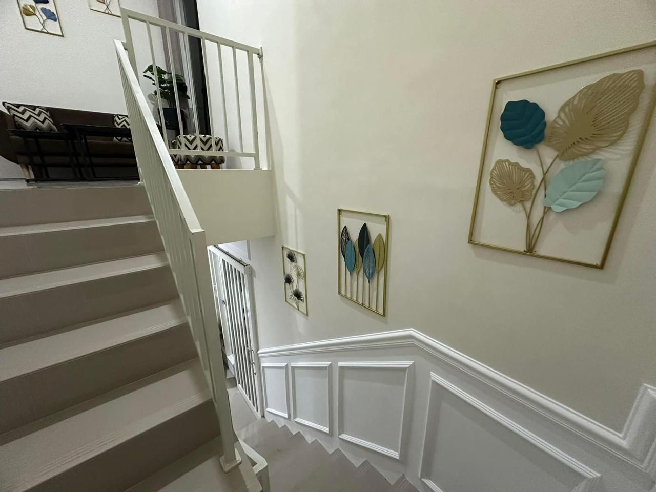 A staircase with white railings and a wall with framed artwork.