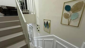 A staircase with white railings and a wall with framed artwork.