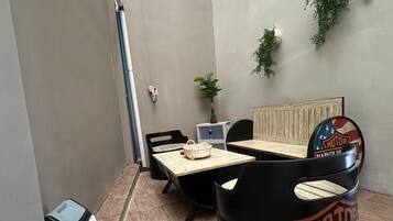 A room with a wooden floor, a Harley-Davidson-themed seating area, a window with a view, and a wall-mounted plant.