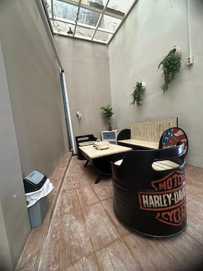 Une pièce dotée d’un plancher en bois, d’un coin salon décoré sur le thème de Harley-Davidson, d’une fenêtre offrant une vue agréable et d’une plante fixée au mur.