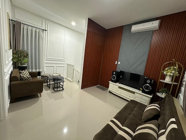 A modern living room with a sofa, a coffee table, a TV, and a speaker system.