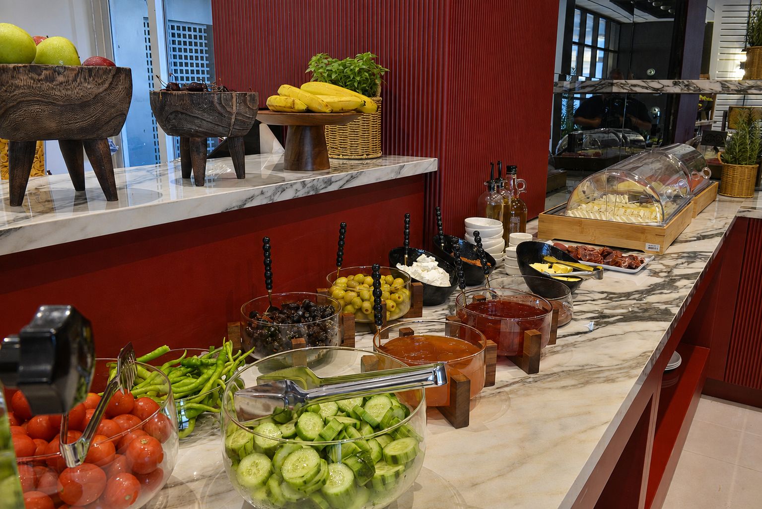 A buffet with various food items including fruits, vegetables, and condiments.