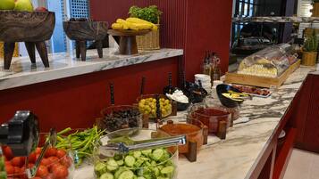 A buffet with various food items including fruits, vegetables, and condiments.