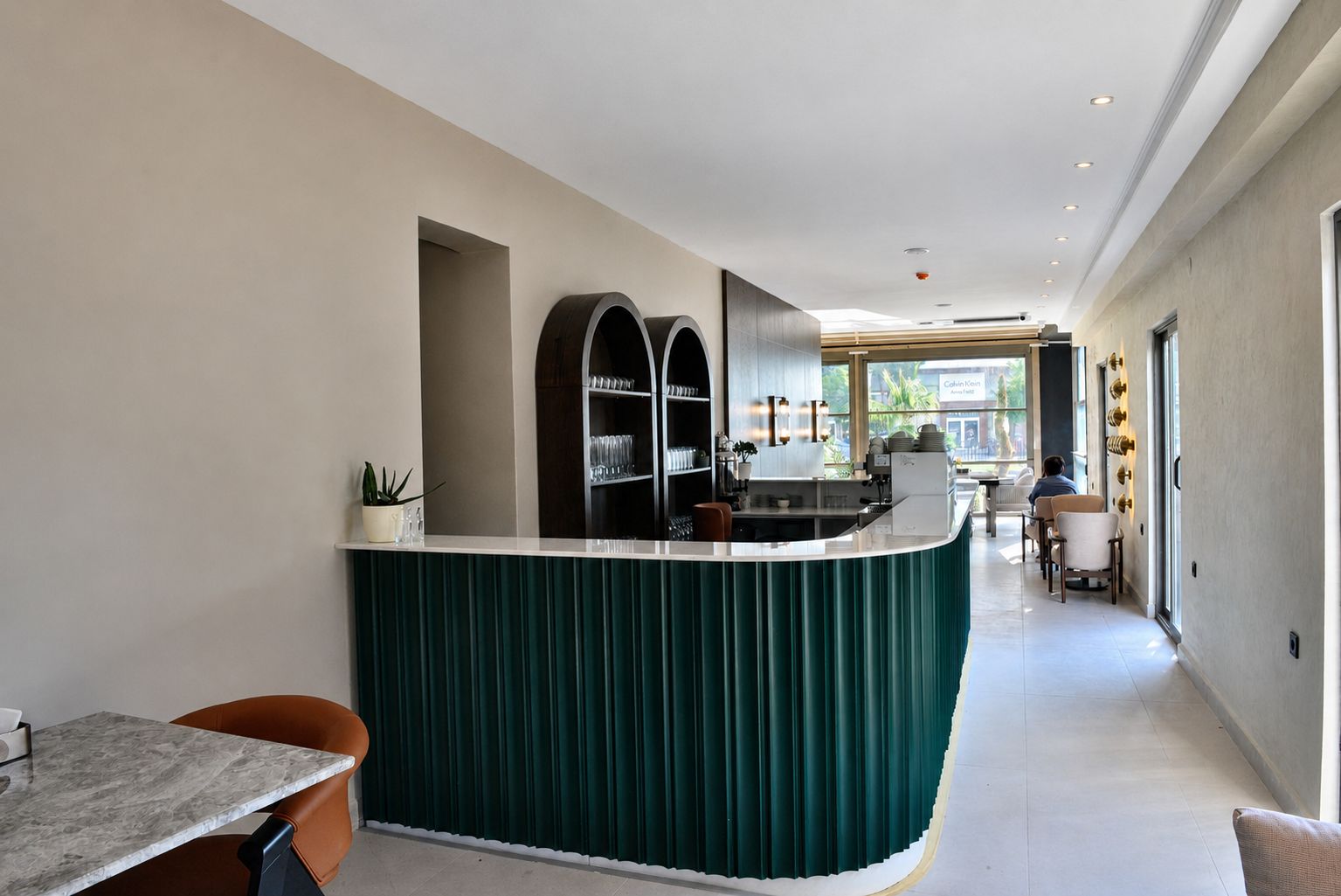 A modern kitchen with a curved island, built-in shelves, and a dining area with a table and chairs.