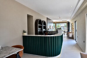 A modern kitchen with a curved island, built-in shelves, and a dining area with a table and chairs.