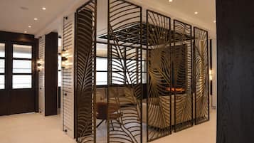 Un interior moderno con un separador decorado con un diseño de hojas, un sofá y una chimenea.