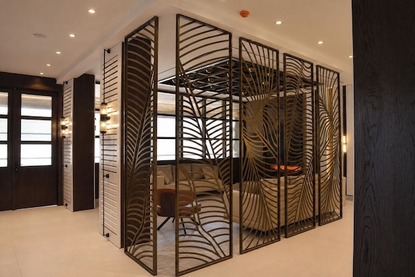 A modern interior with a partition featuring a leaf-like design, a sofa, and a fireplace.