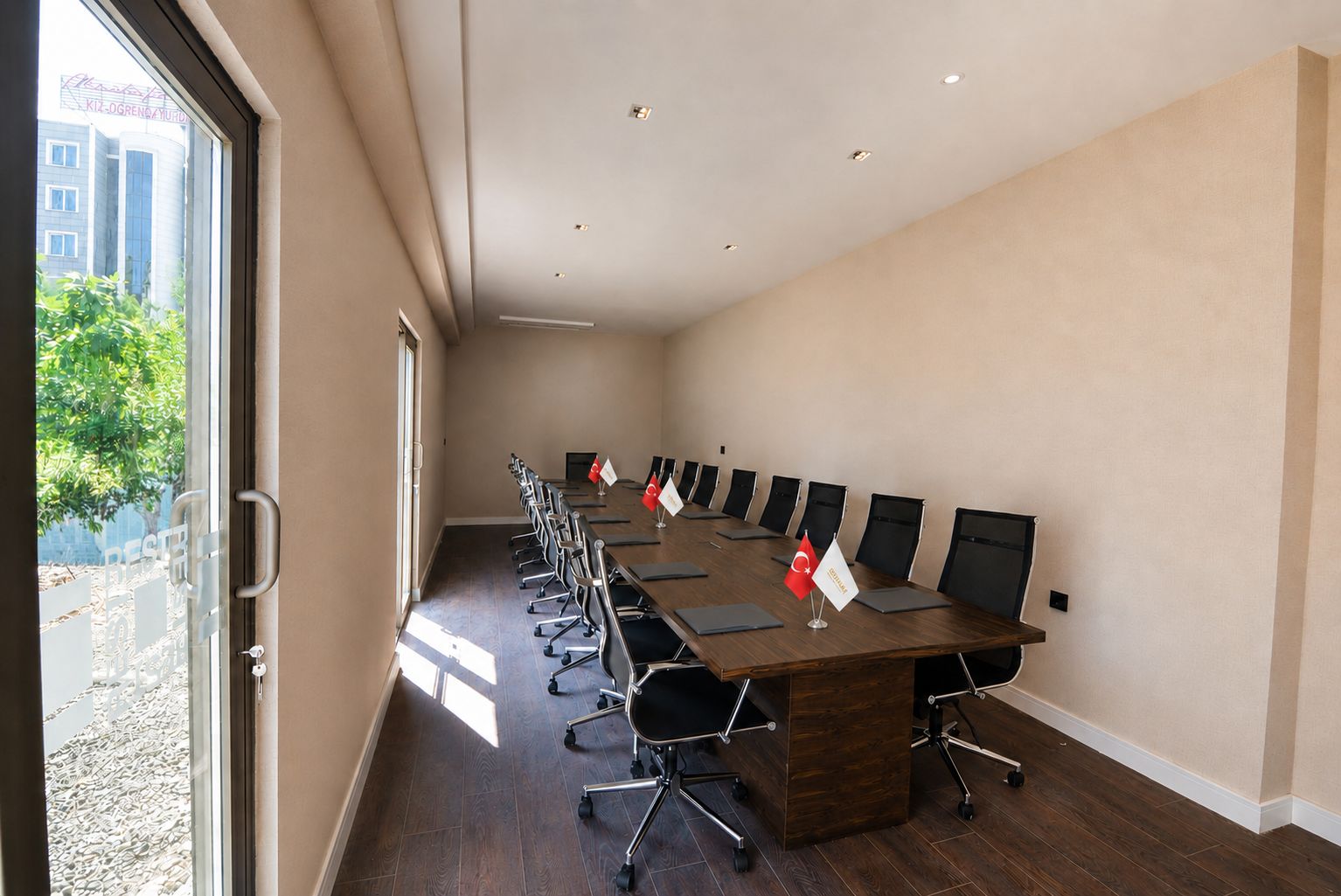 A conference room with a long table, chairs, and flags.