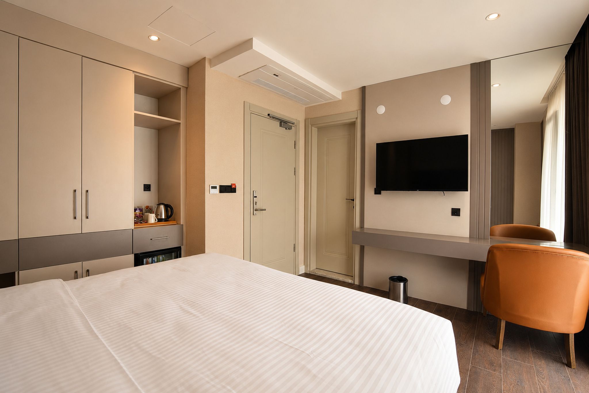 A hotel room with a bed, wardrobe, television, and a chair.