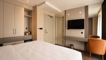 A hotel room with a bed, wardrobe, television, and a chair.