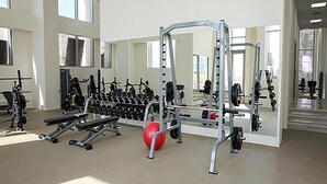 Ett gym med utrustning för styrketräning, en bänk och en röd medicinboll.
